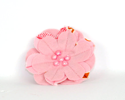 Pink soft felt flower brooch with printed cotton inset petals and pearl beads at the centre. 